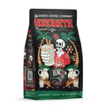 The front of a 12 ounce bag of Bones Coffee Company Horchata coffee. Its flavor is horchata, and it has a skeleton holding out a glass of horchata between palm trees and lights on the art.
