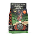 The front of a 12 ounce bag of Bones Coffee Company Highland Grog decaf coffee. Its flavor is caramel and butterscotch, and it has a skeleton wearing a kilt playing bagpipes on a hill on the art.