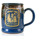 The front of the Bones Coffee Company S’morey Time Handthrown Mug. It has the S’morey Time art on the golden medallion. The mug is blue colored with a cinnamon and white glaze.